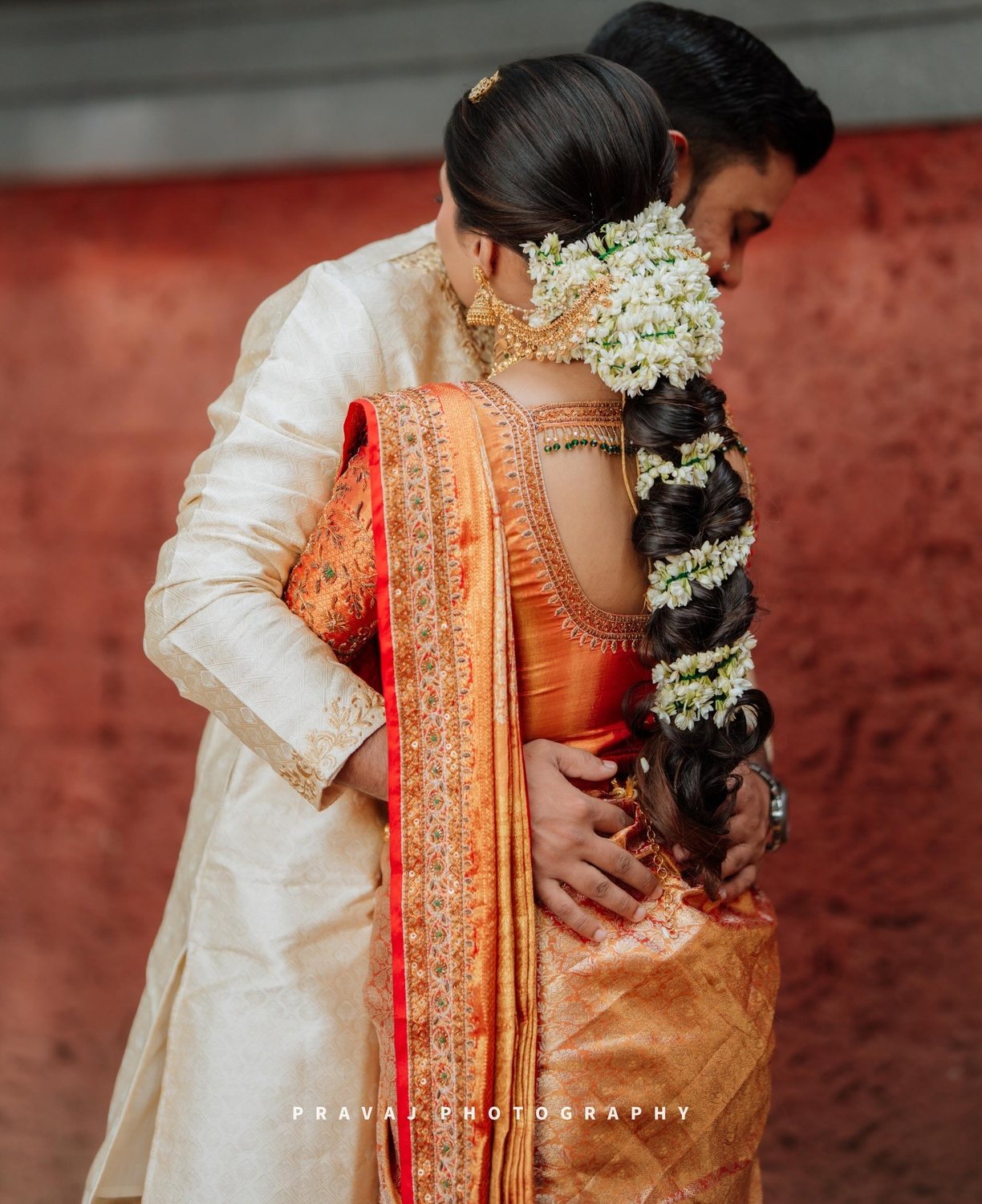 A Malayali couple in kasavu and gold — the groom in white mundu, the bride in a gold-bordered silk