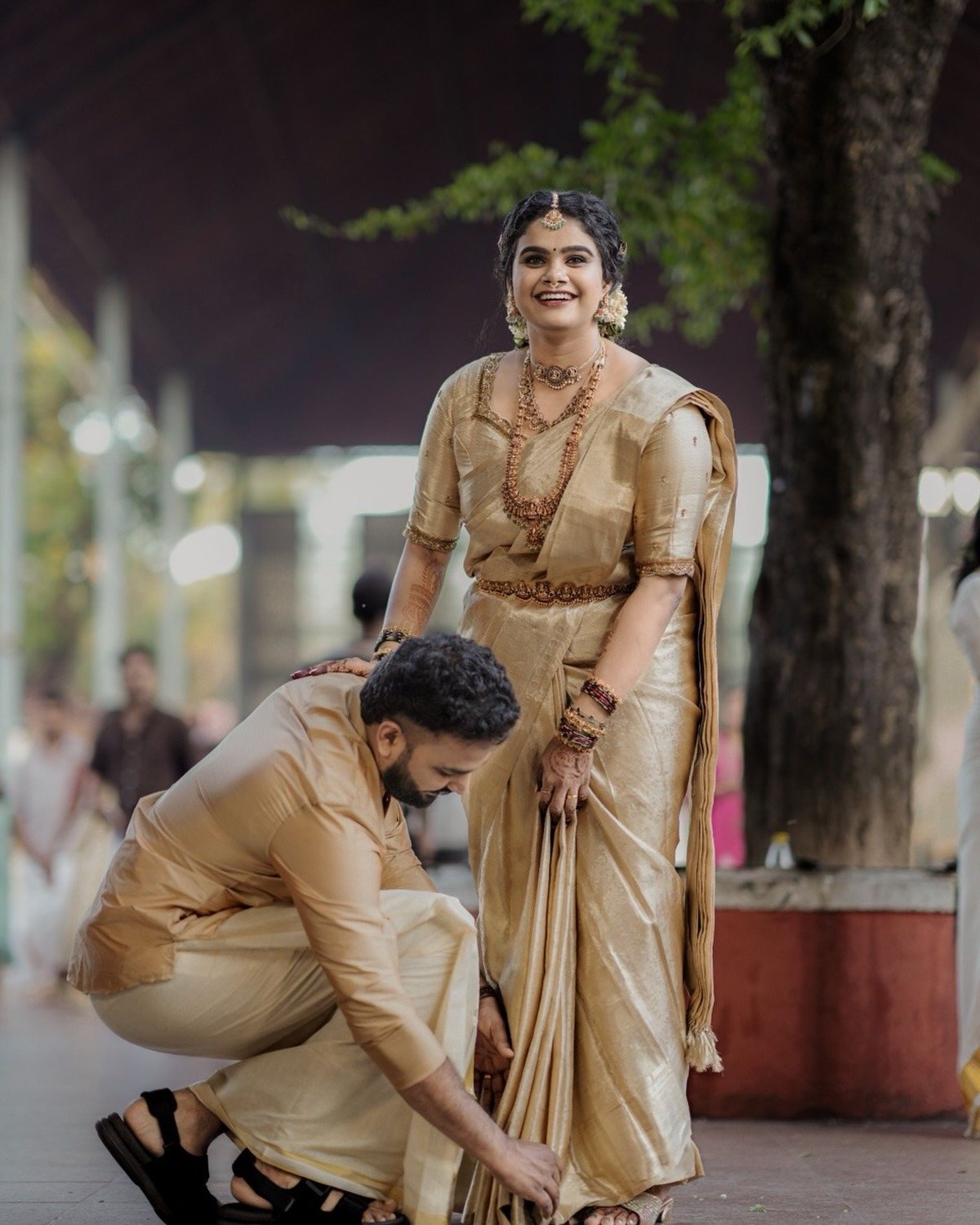 Groom adjusting the bride's saree pleats